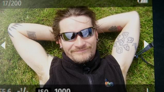 Mark Kennedy laying down on a grassy bank with his hands behind his head