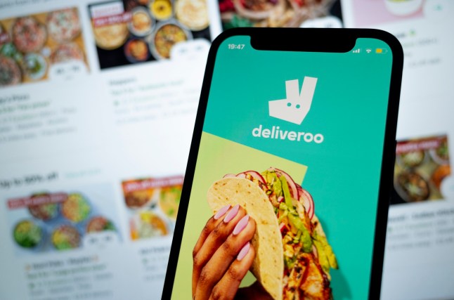 In this photo illustration, an iPhone displays the app and logo of fast food delivery giant Deliveroo with the desktop version in the background, where customers can order food for delivery from local restaurants and convenience shops on 8th March, 2022 in Leeds, United Kingdom. (photo by Daniel Harvey Gonzalez/In Pictures via Getty Images)