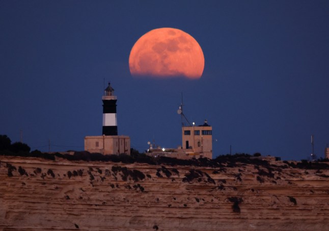A full moon known as the "Flower Moon" rises over Delimara Point lighthouse, as seen from Birzebbuga, Malta, May 12, 2025. REUTERS/Darrin Zammit Lupi